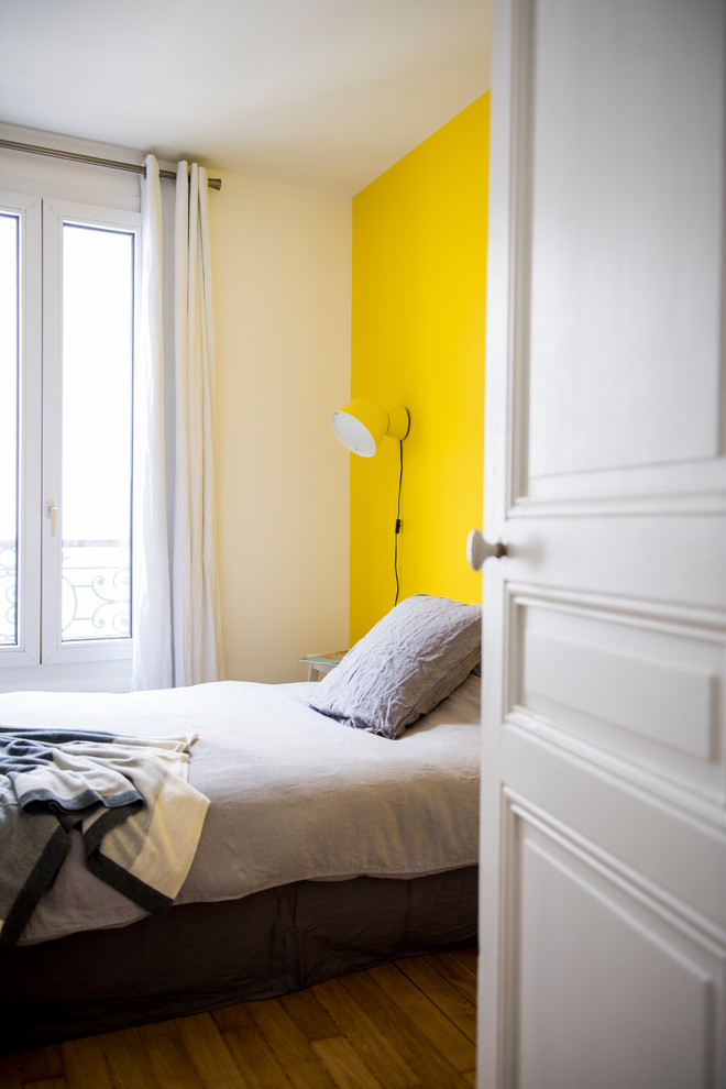 Ejemplo de dormitorio principal tradicional renovado pequeño sin chimenea con paredes amarillas, suelo de madera clara y suelo marrón