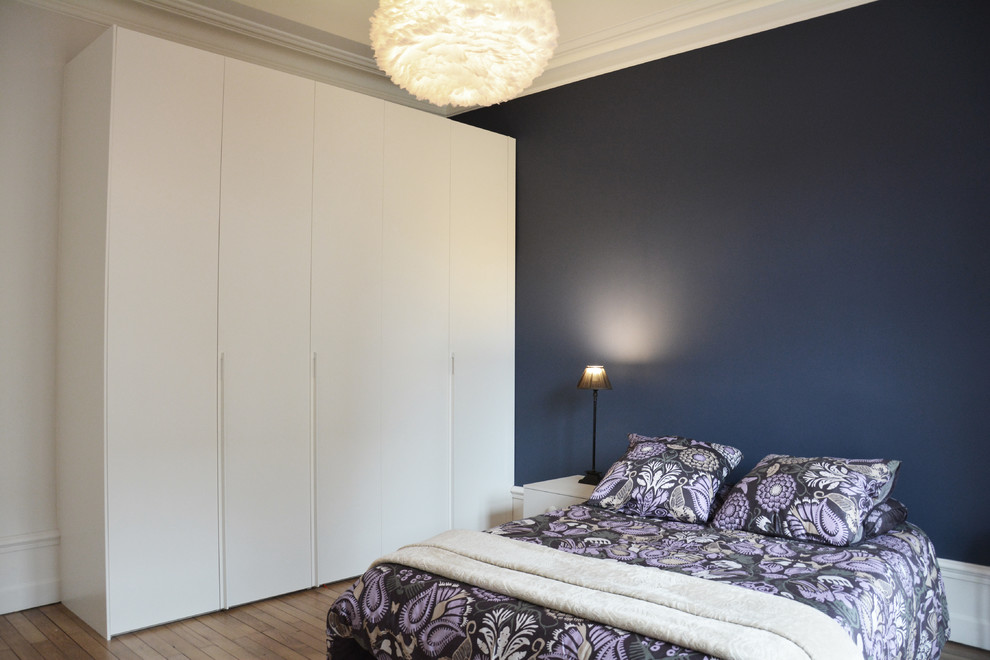 Foto de dormitorio principal moderno de tamaño medio sin chimenea con paredes azules y suelo de madera clara