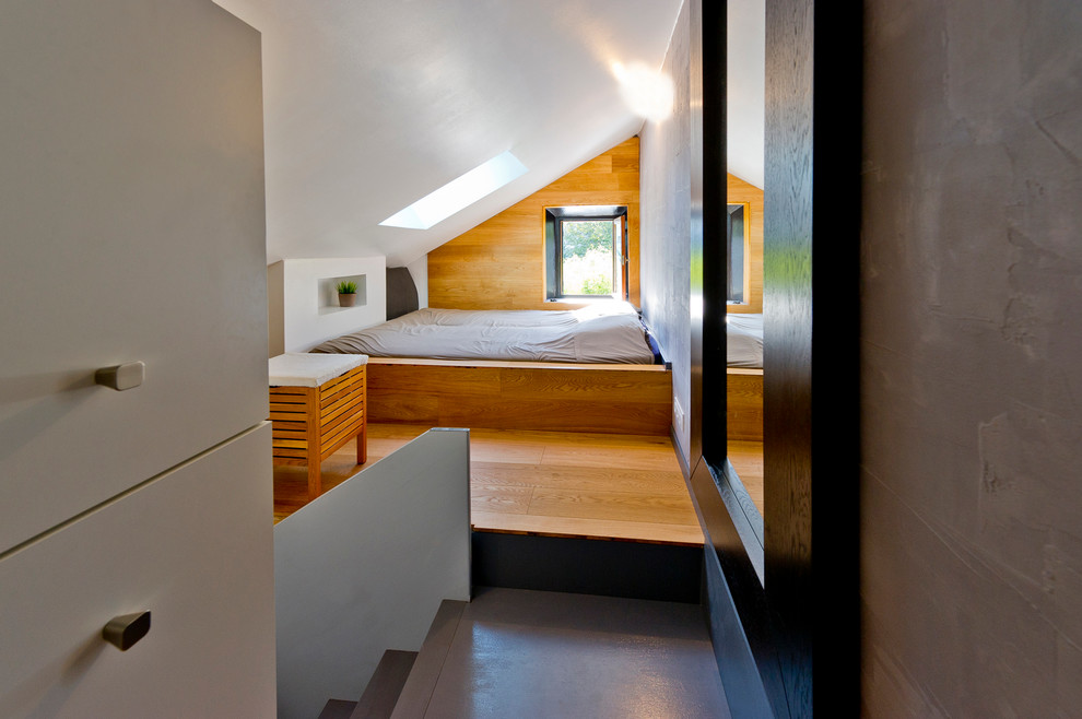 Modelo de dormitorio principal actual sin chimenea con paredes blancas y suelo de madera en tonos medios