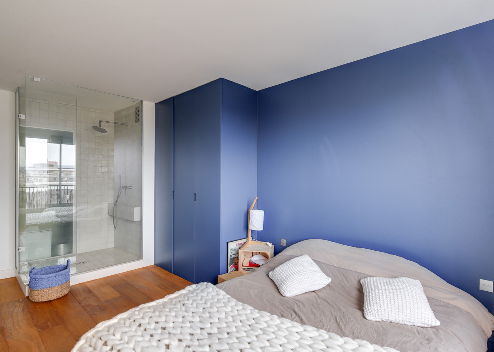 Ispirazione per una grande camera matrimoniale design con pareti blu, pavimento in legno massello medio, nessun camino e pavimento marrone