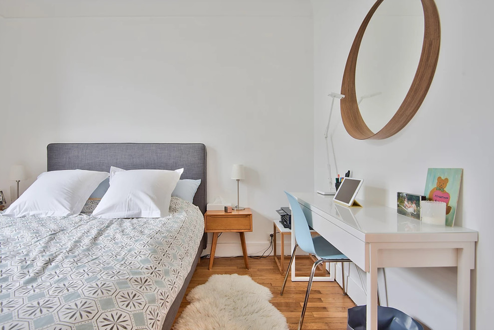 Mittelgroßes Retro Hauptschlafzimmer ohne Kamin mit weißer Wandfarbe, braunem Holzboden und braunem Boden in Paris
