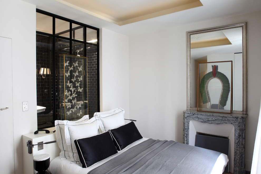 Immagine di una camera degli ospiti eclettica con pareti bianche e camino classico