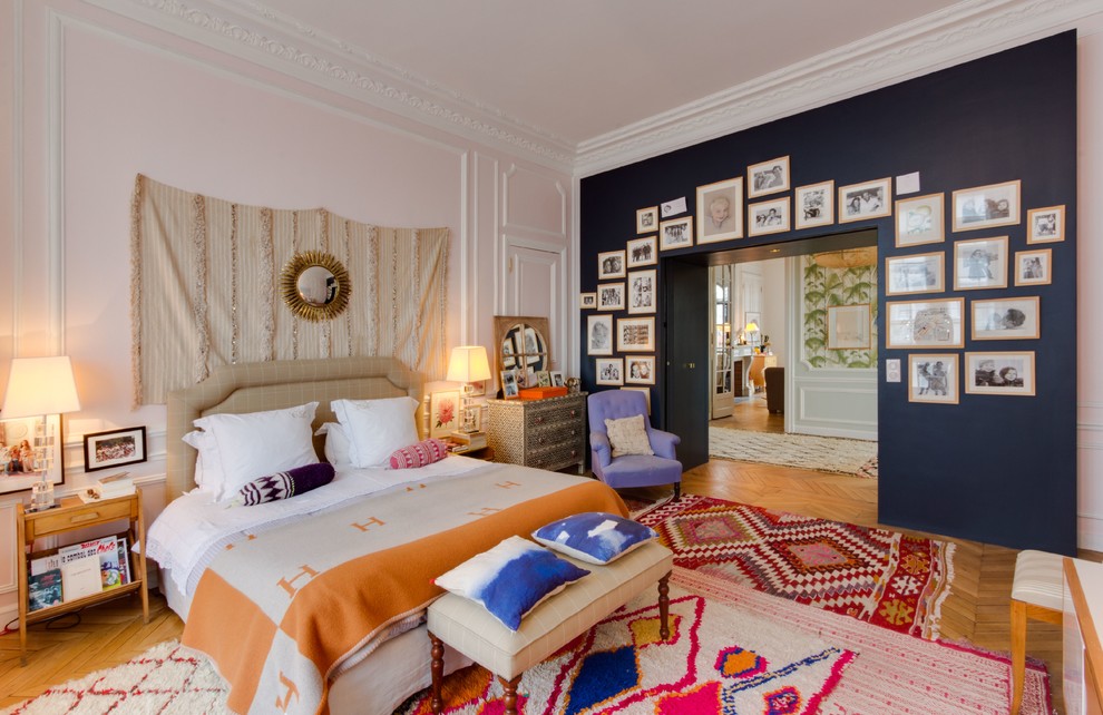 Modelo de dormitorio principal bohemio con paredes rosas, suelo de madera en tonos medios y suelo marrón
