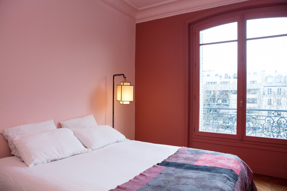 Cette image montre une chambre parentale design de taille moyenne avec un mur rose et parquet foncé.