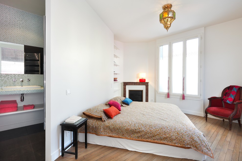 Stilmix Schlafzimmer mit weißer Wandfarbe, braunem Holzboden und Eckkamin in Paris