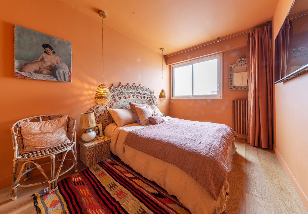 Imagen de dormitorio principal actual de tamaño medio sin chimenea con parades naranjas, suelo de madera clara y suelo beige