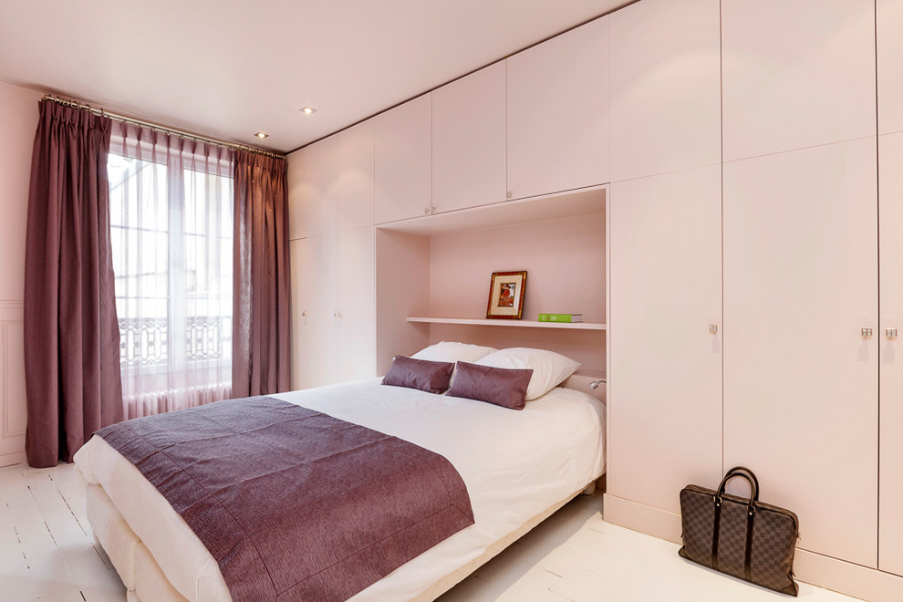 Modelo de dormitorio principal actual de tamaño medio con paredes beige, suelo de madera pintada y suelo blanco