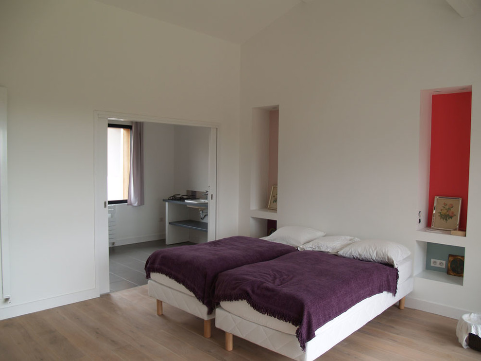 Ejemplo de habitación de invitados actual de tamaño medio con paredes blancas y suelo de madera clara