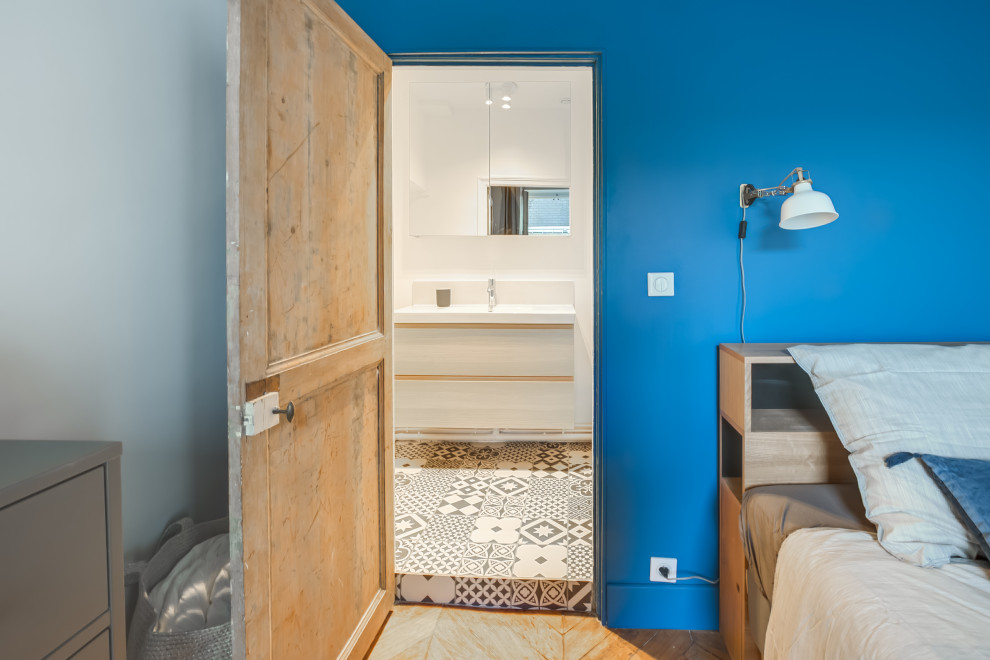 На фото: спальня в скандинавском стиле с синими стенами, паркетным полом среднего тона, двусторонним камином и коричневым полом с