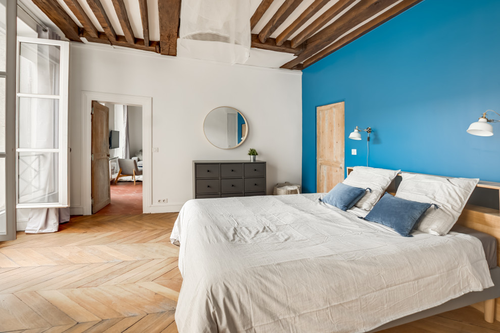 Idées déco pour une chambre scandinave avec un mur bleu, un sol en bois brun, une cheminée double-face et un sol marron.