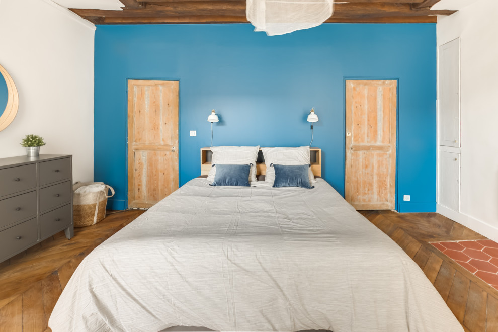 Exemple d'une chambre scandinave avec un mur bleu, un sol en bois brun, une cheminée double-face et un sol marron.