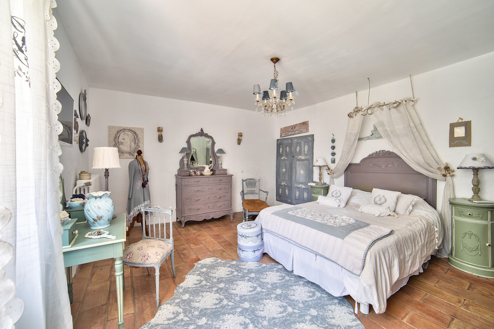 На фото: хозяйская спальня в стиле шебби-шик с белыми стенами и полом из терракотовой плитки без камина