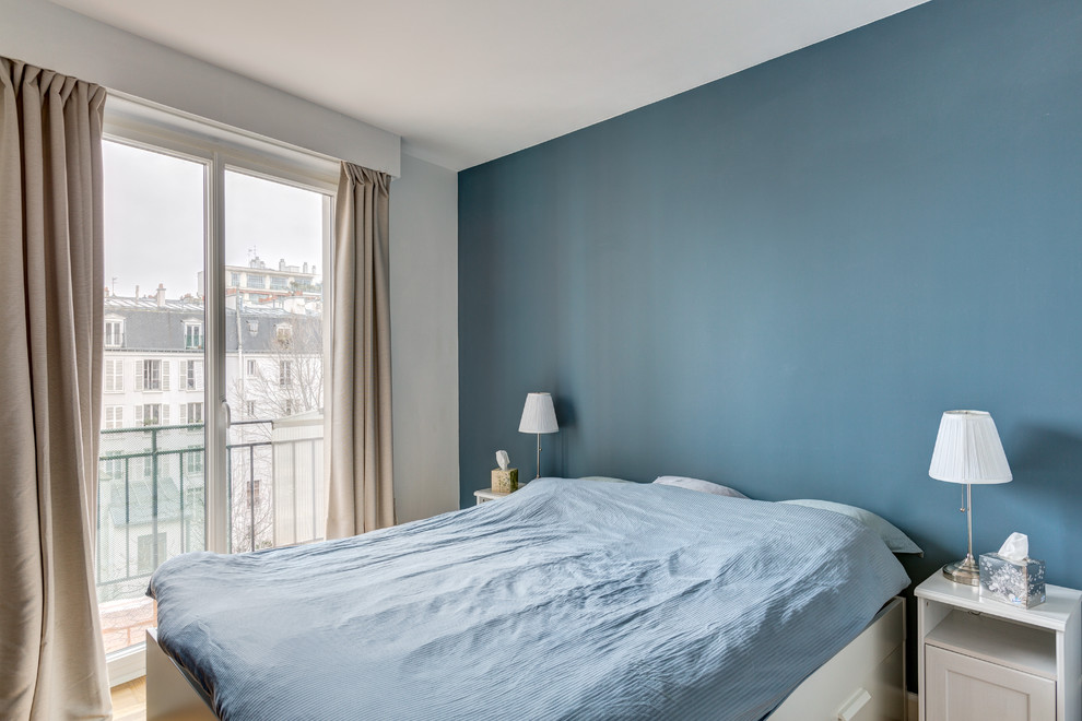 Réalisation d'une chambre parentale nordique de taille moyenne avec un mur bleu, un sol en bois brun, aucune cheminée et un sol beige.