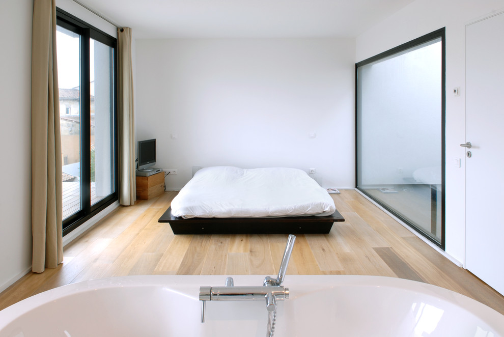 Aménagement d'une chambre parentale contemporaine de taille moyenne avec un mur blanc et parquet clair.