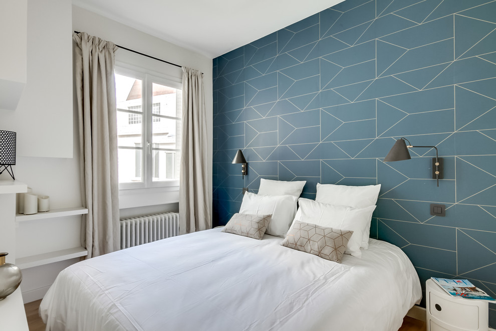 Scandi guest bedroom in Paris with blue walls, light hardwood flooring, beige floors and a feature wall.