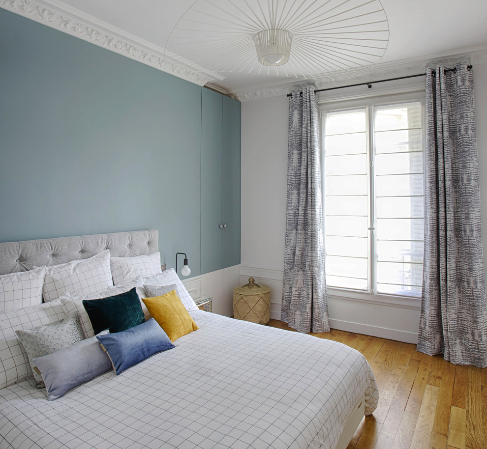 Imagen de dormitorio contemporáneo con paredes azules, suelo de madera en tonos medios y suelo marrón
