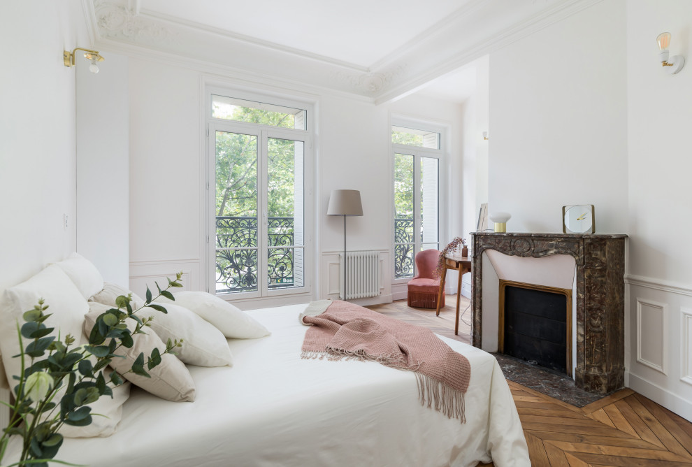 Стильный дизайн: хозяйская спальня в современном стиле с белыми стенами, паркетным полом среднего тона и стандартным камином - последний тренд
