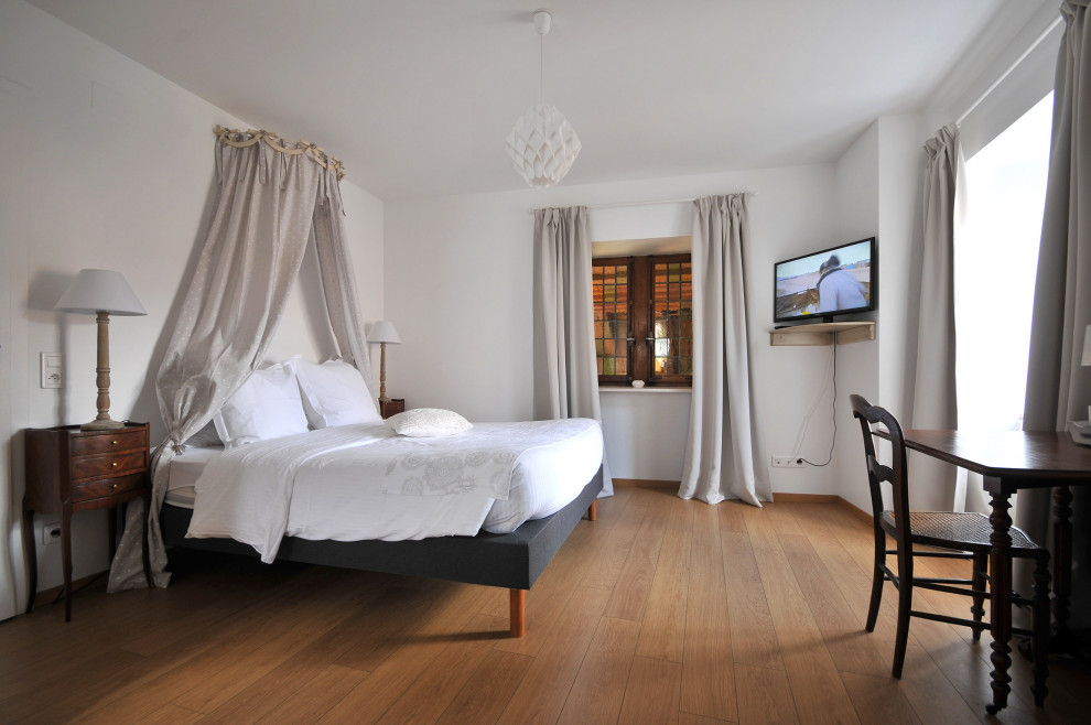 Foto de dormitorio principal minimalista grande con paredes blancas y suelo de madera en tonos medios
