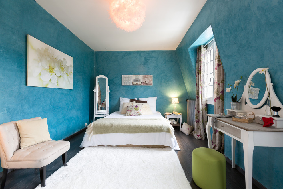 Aménagement d'une chambre éclectique avec un mur bleu, parquet foncé et un sol marron.