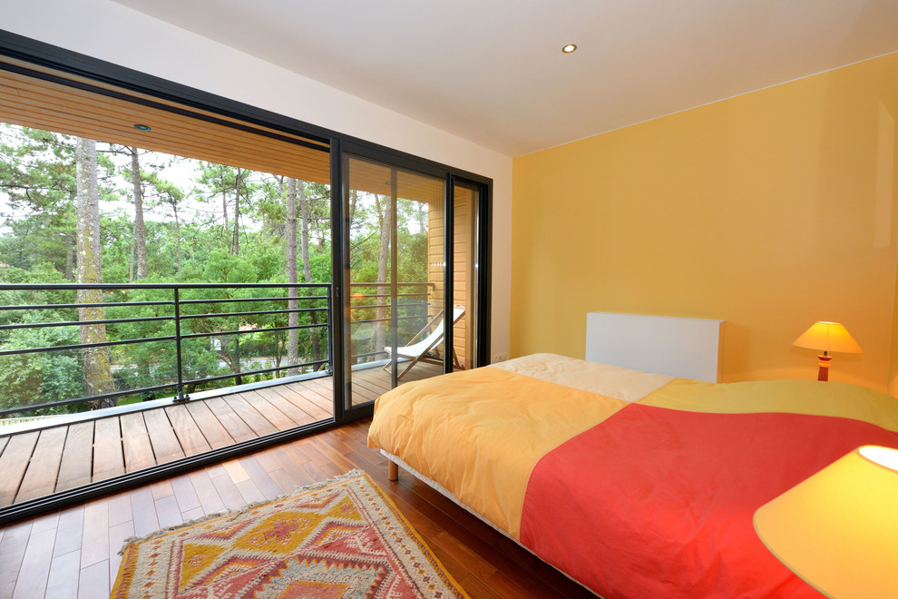 Exemple d'une grande chambre parentale tendance avec un mur jaune, parquet foncé, aucune cheminée et un sol marron.