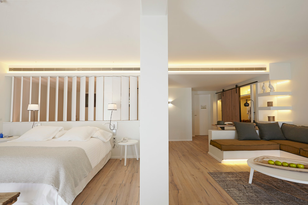 Großes Skandinavisches Hauptschlafzimmer ohne Kamin mit weißer Wandfarbe und braunem Holzboden in Toulouse