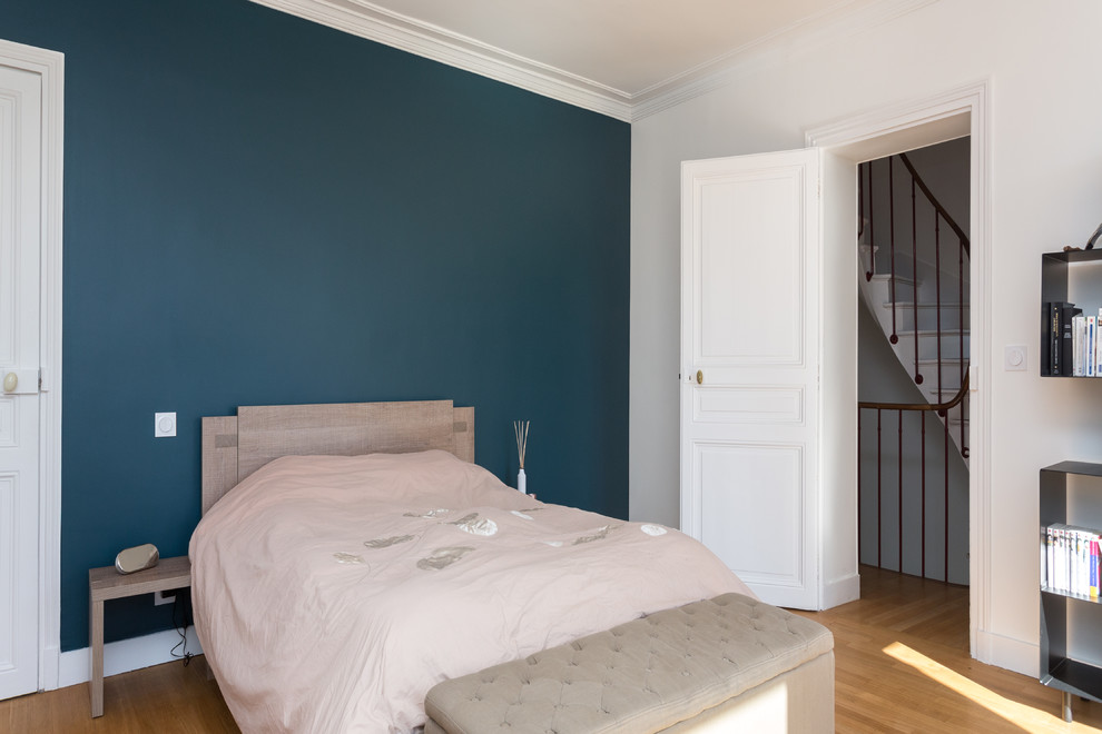 ロンドンにある中くらいなモダンスタイルのおしゃれな主寝室 (青い壁、無垢フローリング、暖炉なし、茶色い床) のインテリア