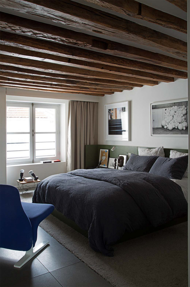 На фото: спальня в современном стиле с белыми стенами, бетонным полом, серым полом и балками на потолке с