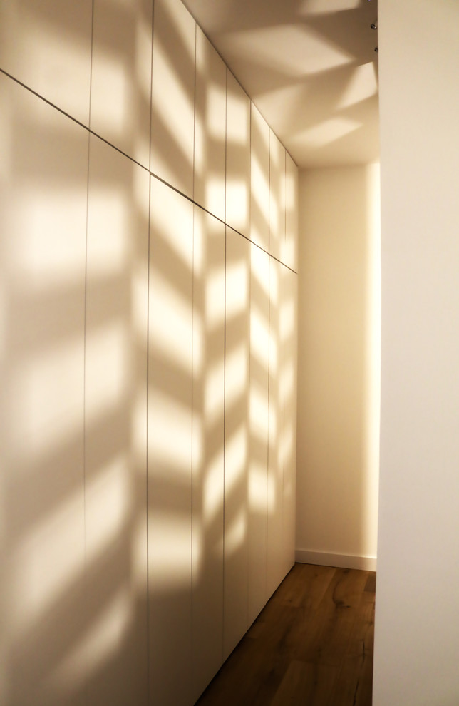 Inspiration pour une grande chambre parentale design avec un mur blanc, parquet clair et un sol marron.