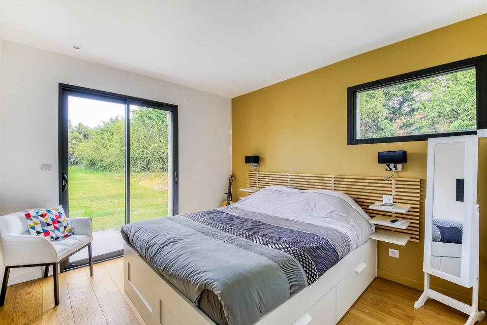 Exempel på ett modernt sovrum, med gula väggar, mellanmörkt trägolv och brunt golv