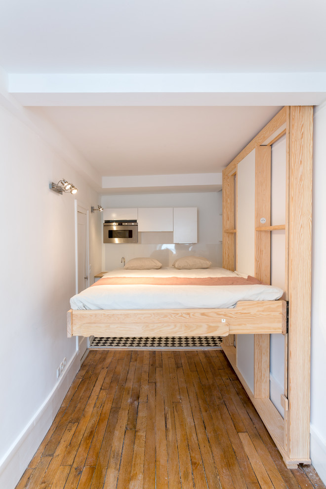 Diseño de dormitorio principal actual pequeño sin chimenea con paredes blancas, suelo de madera en tonos medios y suelo beige
