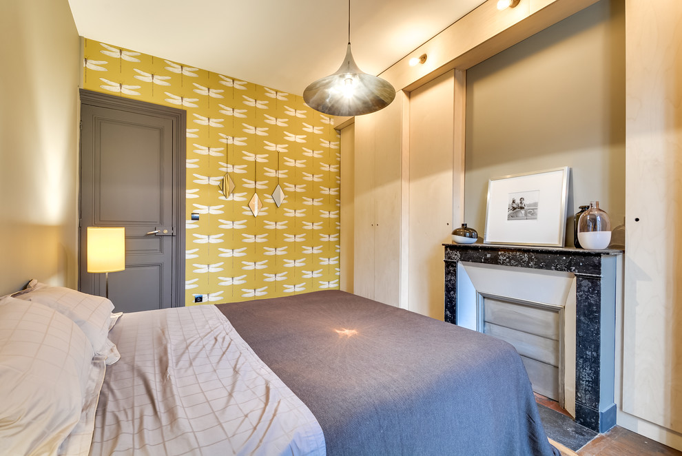 Idées déco pour une chambre parentale contemporaine de taille moyenne avec un sol en bois brun, une cheminée standard, un mur jaune et un manteau de cheminée en pierre.