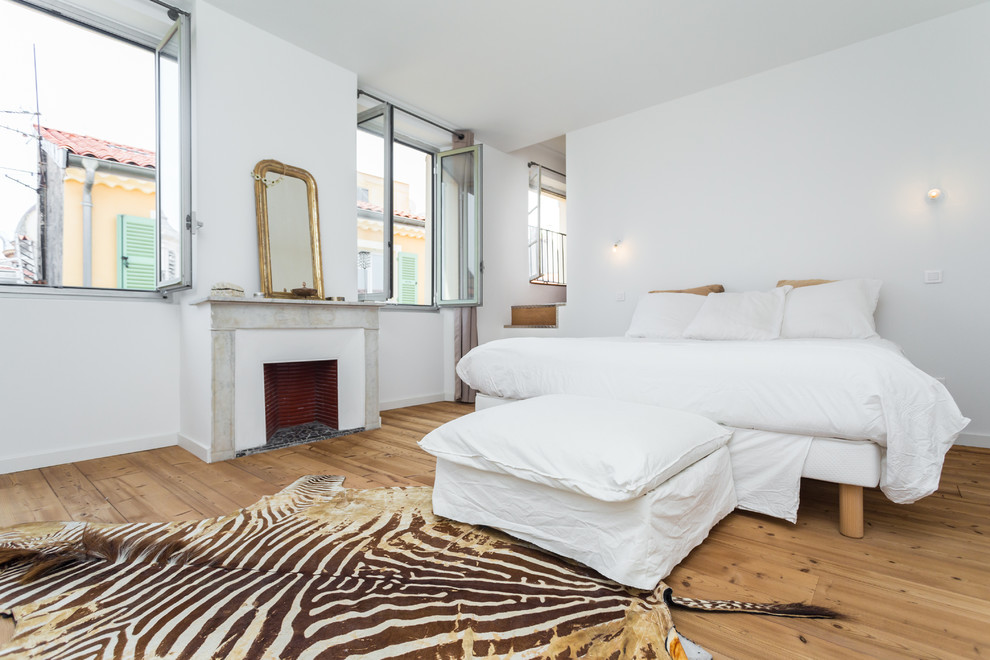 Großes Stilmix Hauptschlafzimmer mit weißer Wandfarbe, hellem Holzboden und Kamin in Nizza