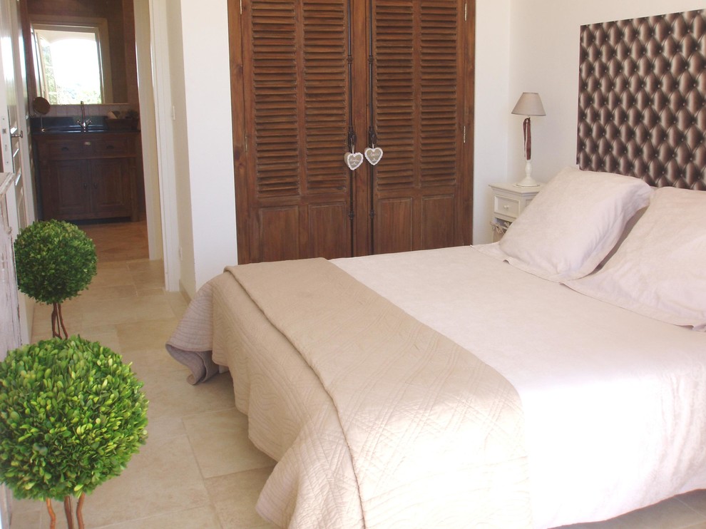 Immagine di una camera matrimoniale mediterranea di medie dimensioni con pareti bianche, pavimento con piastrelle in ceramica, cornice del camino in legno e pavimento beige