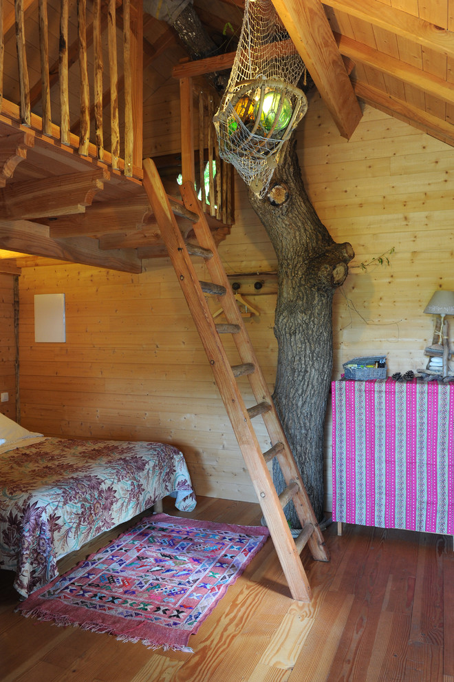 Ejemplo de dormitorio campestre de tamaño medio con suelo de madera en tonos medios y paredes marrones
