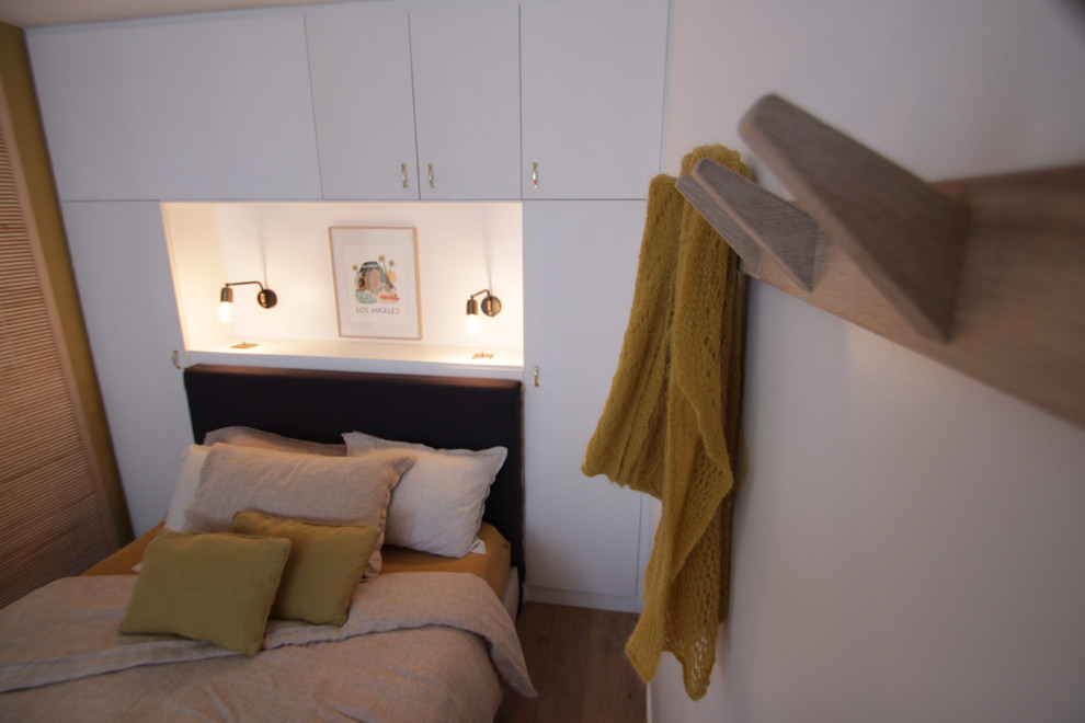 Kleines Retro Hauptschlafzimmer mit weißer Wandfarbe und hellem Holzboden in Paris
