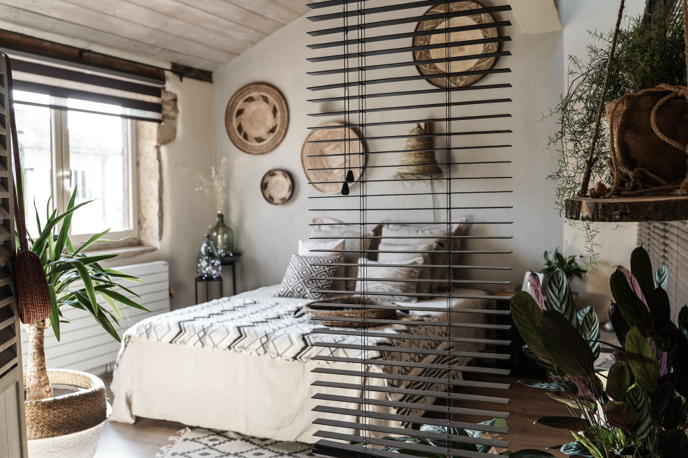 Modelo de dormitorio exótico con paredes grises, suelo laminado y suelo beige
