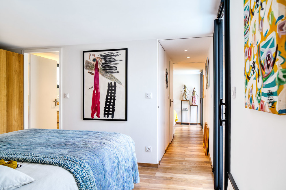 Imagen de dormitorio principal contemporáneo de tamaño medio con paredes blancas, suelo de madera clara y suelo beige