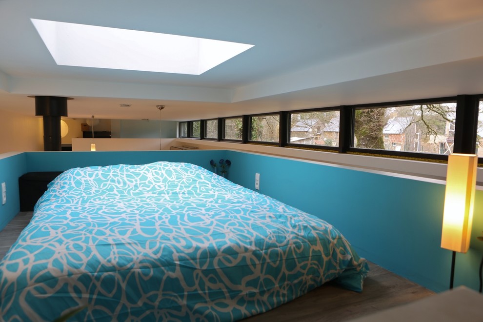 Aménagement d'une petite chambre mansardée ou avec mezzanine contemporaine avec un mur bleu et parquet clair.