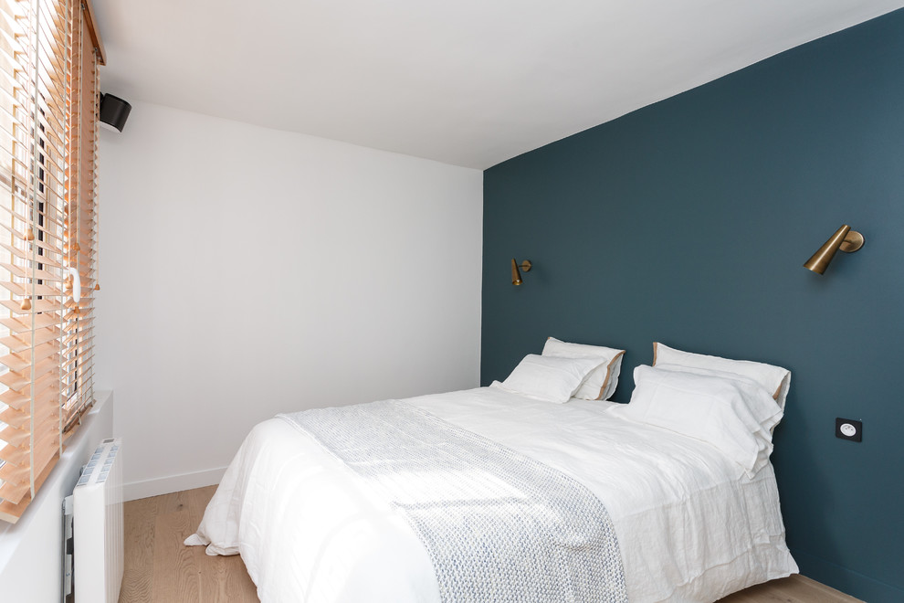 Idée de décoration pour une chambre parentale minimaliste de taille moyenne avec un mur bleu, parquet clair, un sol beige et aucune cheminée.