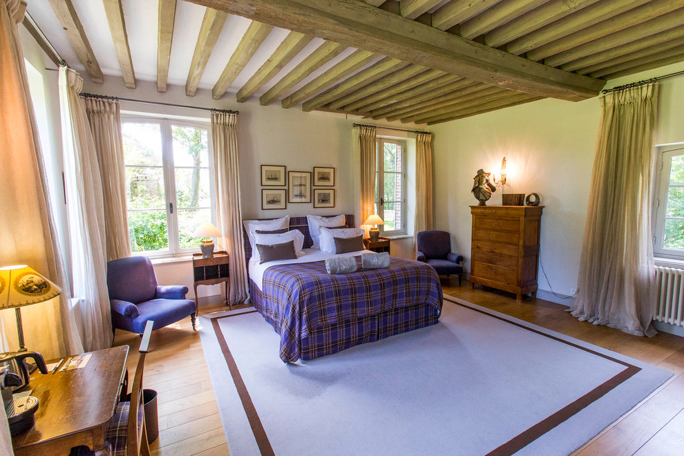 Foto de dormitorio principal y blanco y madera clásico renovado grande sin chimenea con paredes blancas, suelo de madera clara, suelo marrón y vigas vistas