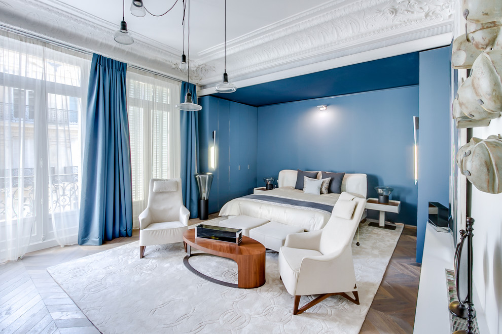 Réalisation d'une chambre parentale haussmannienne design avec un mur bleu, un sol en bois brun et un sol marron.