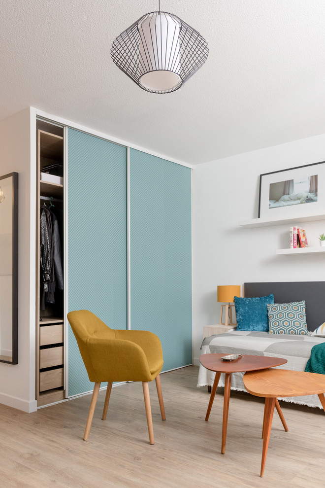 Cette image montre une petite chambre d'amis nordique avec un mur bleu, sol en stratifié et un sol beige.