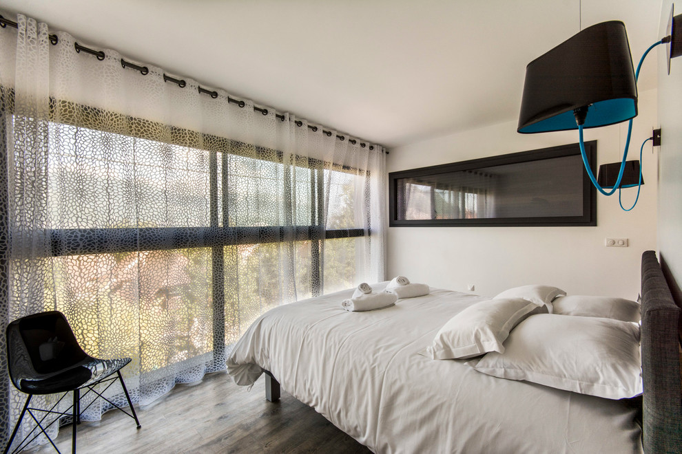 Foto de dormitorio principal moderno de tamaño medio con paredes blancas y suelo de madera en tonos medios