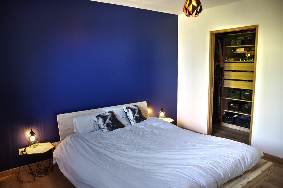 Photo of a medium sized contemporary master bedroom in Lyon with blue walls, laminate floors and brown floors.