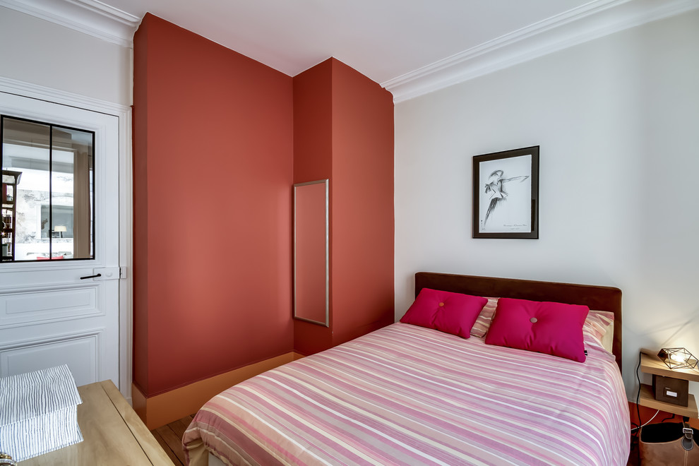 Cette image montre une chambre rustique avec un mur rouge.