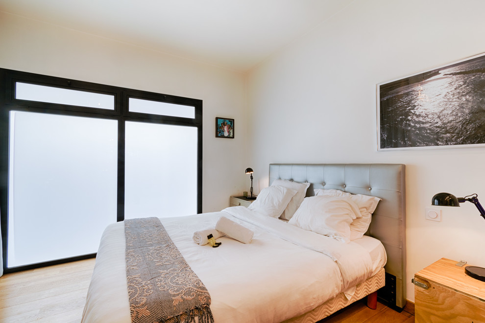 Стильный дизайн: большая гостевая спальня (комната для гостей) в современном стиле с белыми стенами, светлым паркетным полом и коричневым полом - последний тренд