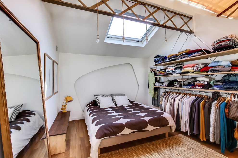 Ejemplo de dormitorio ecléctico con paredes blancas y suelo de madera clara