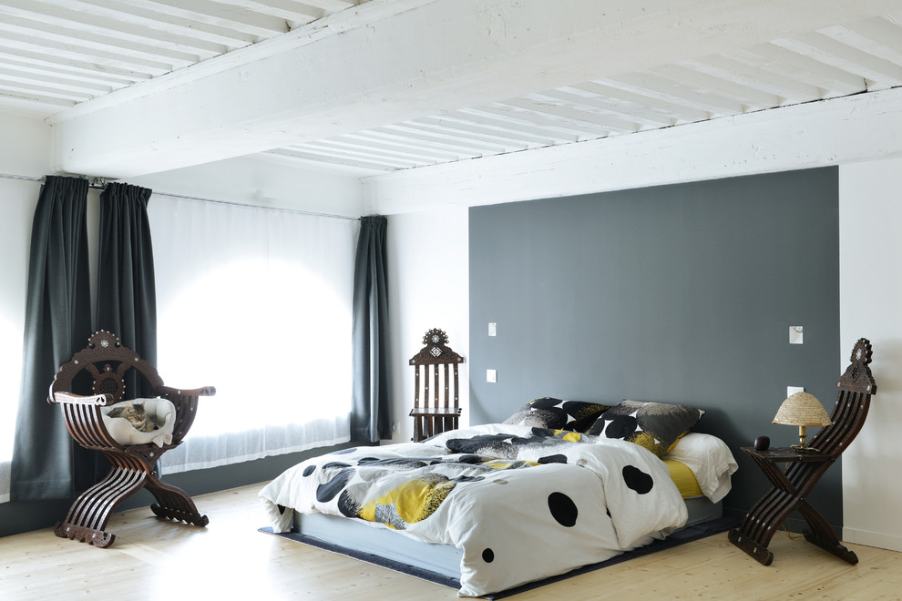 Photo of a bohemian bedroom in Lyon with grey walls, light hardwood flooring, beige floors and a feature wall.