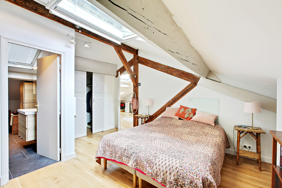 Immagine di una camera matrimoniale tropicale di medie dimensioni con pareti bianche, pavimento in legno massello medio e pavimento marrone