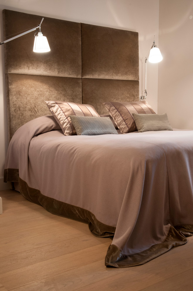 Ejemplo de dormitorio principal actual de tamaño medio con paredes blancas y suelo de madera en tonos medios